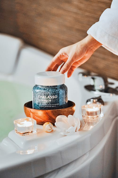 An image of candles and a black jar on the edge of a bathtub 