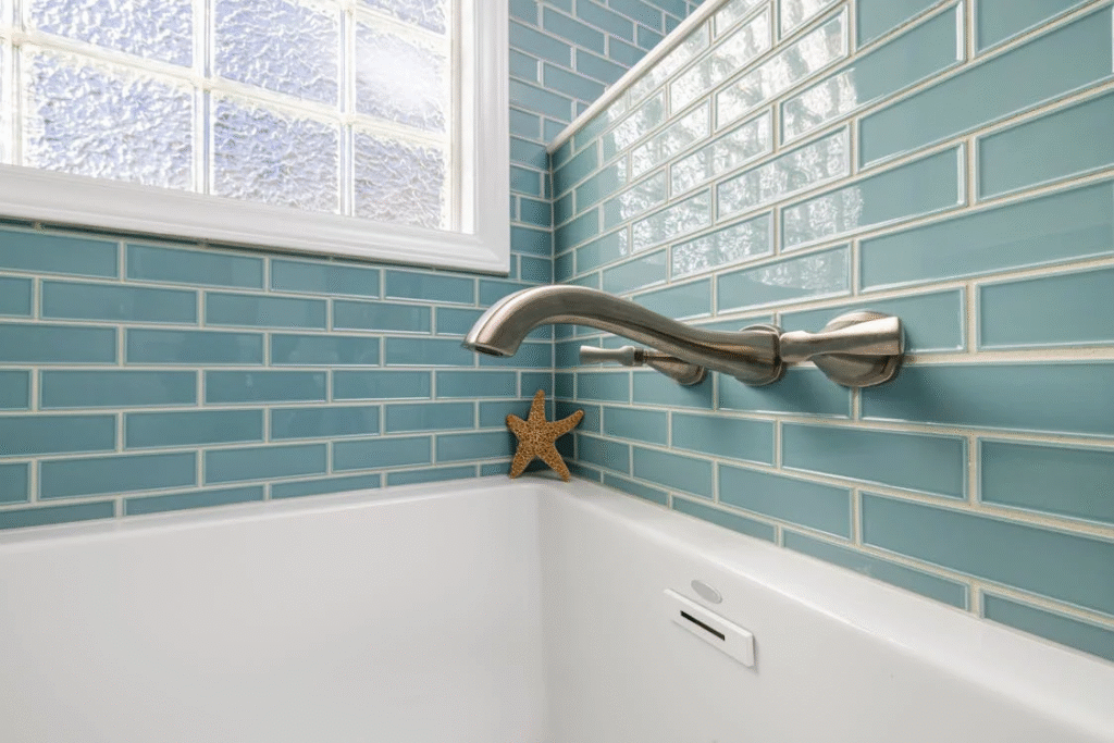 close up of a faucet over a bathtub in a blue tiled bathroom