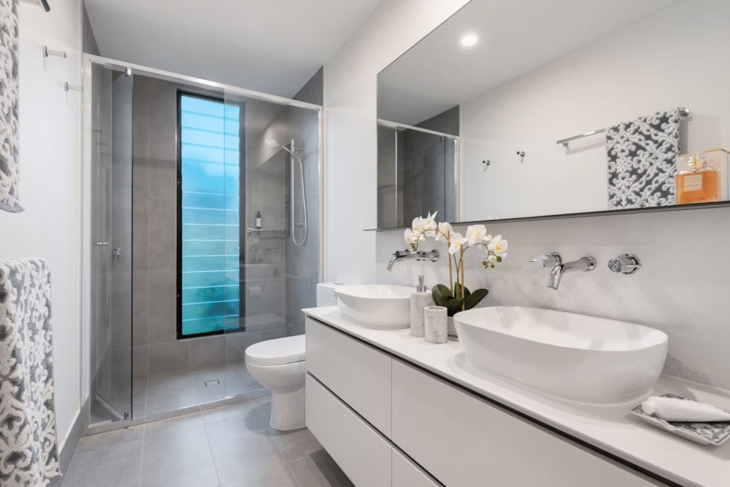 white bathroom with two sinks and a glass-enclosed walk-in shower