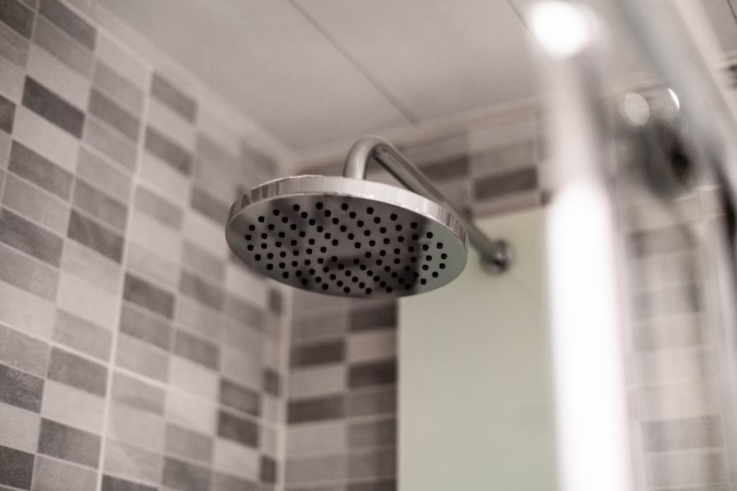 close up of a grey showerhead with tiled walls