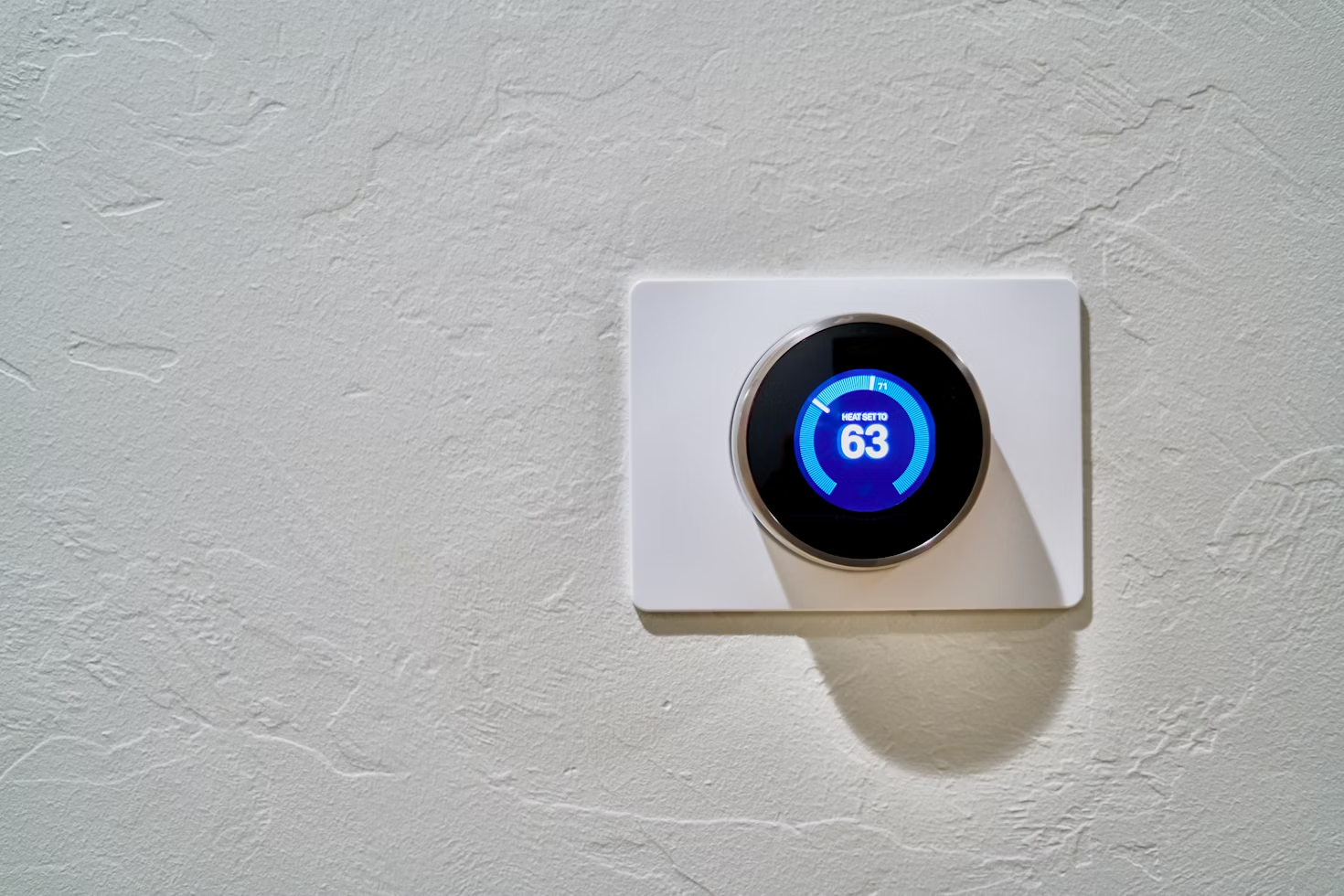 white and black digital thermostat placed on a textured wall