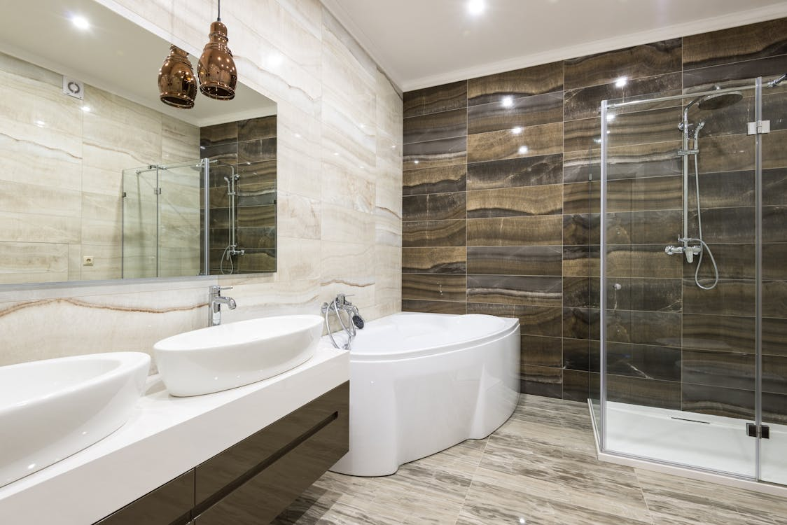a bathroom with space being taken up by 2 sinks, a bathtub and a walk-in shower