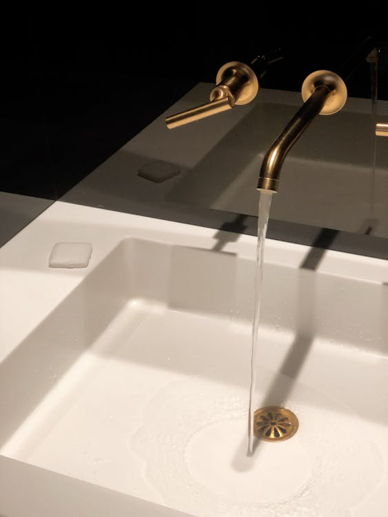 A close-up of water flowing from a bronze-colored bathroom faucet.