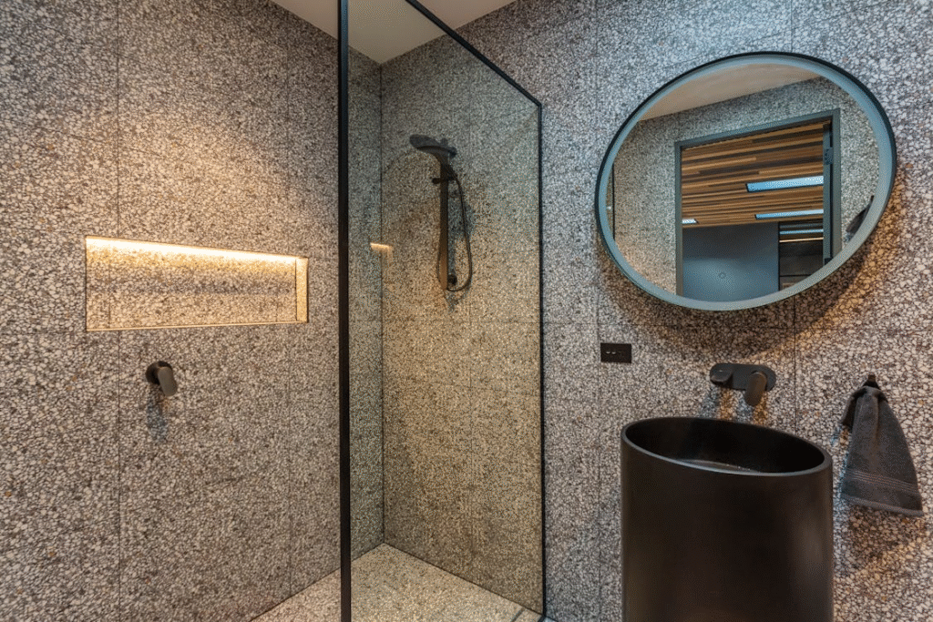 Elegant bathroom with textured wall finishes, modern fixtures, and a clean, warm-toned color palette