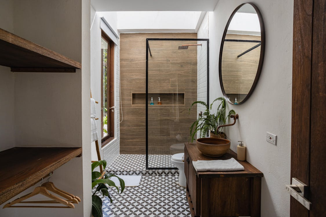 A modern bathroom with a walk-in shower featuring a glass door and metal frame.