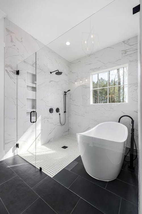 Bathroom with a large tub and black tile walls, featuring a bold and modern design
